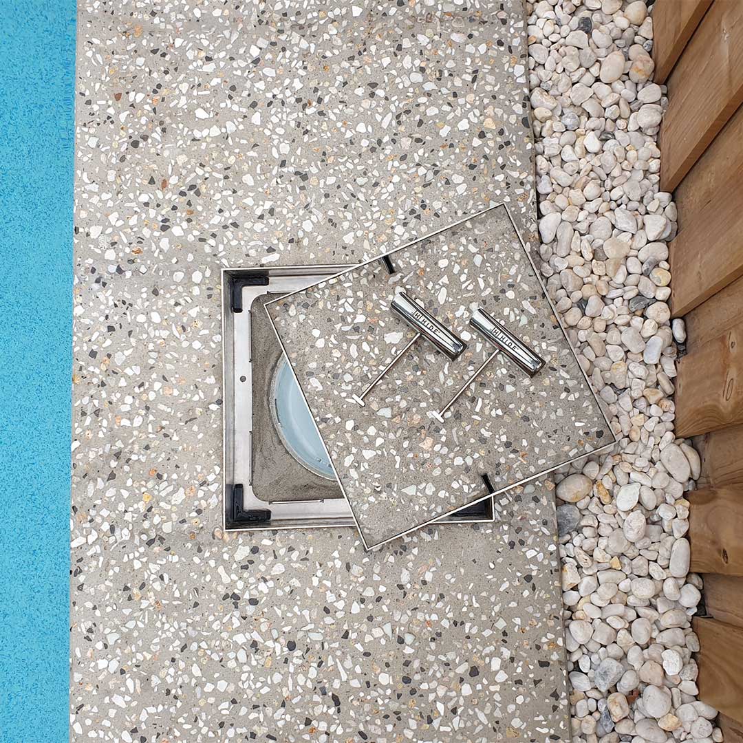 HIDE Concrete Skimmer Cover with honed exposed aggregate finish next to pool.