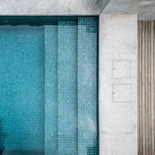 Two HIDE stainless steel skimmer covers set flush in pool coping, with grout lines aligned beside the water and timber decking.