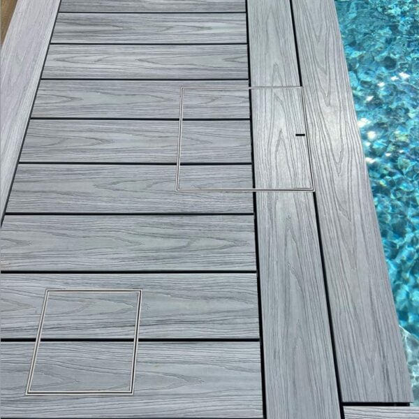 Two HIDE Skimmer Covers in grey composite decking beside pool.