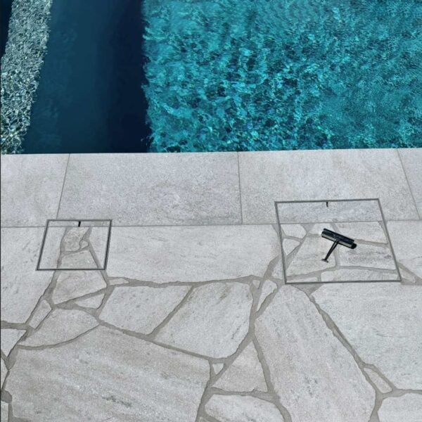 HIDE stainless steel Skimmer Cover and Access Cover set flush in pool coping; stone inlays follow the crazy paving pattern, shown with HIDE lifting key.