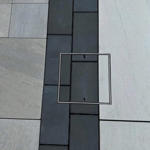 Stainless steel HIDE Access Cover with dual coloured paving inlay; continuing the surrounding paving pattern through the HIDE Cover for a continuous finish.