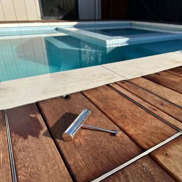 HIDE Stainless Steel Skimmer Cover with timber decking inlay and HIDE Safety key sitting on top.