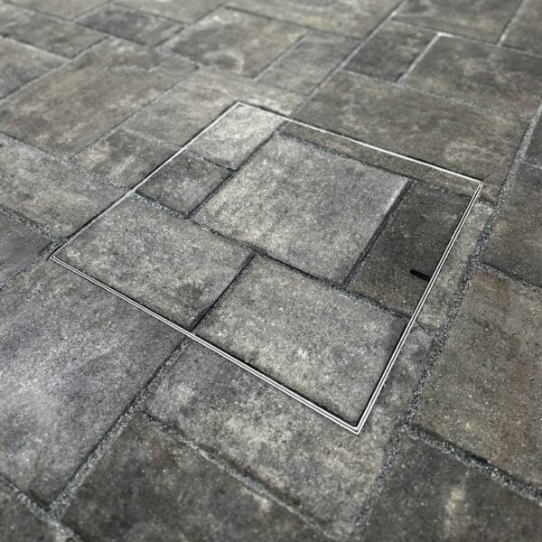 HIDE stainless steel Skimmer Cover with paver pattern inlay set flush in paving; paving pattern continues through the cover to match the surrounding pattern.