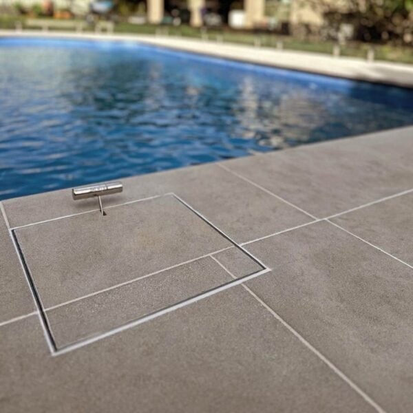 Stainless Steel HIDE Skimmer Cover with tile inlay and tile pattern running through next to modern pool.