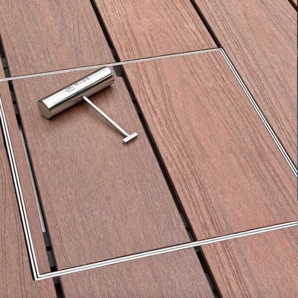 HIDE stainless steel skimmer cover set flush in timber deck boards; board joints continue through the cover, shown with safety lifting key.