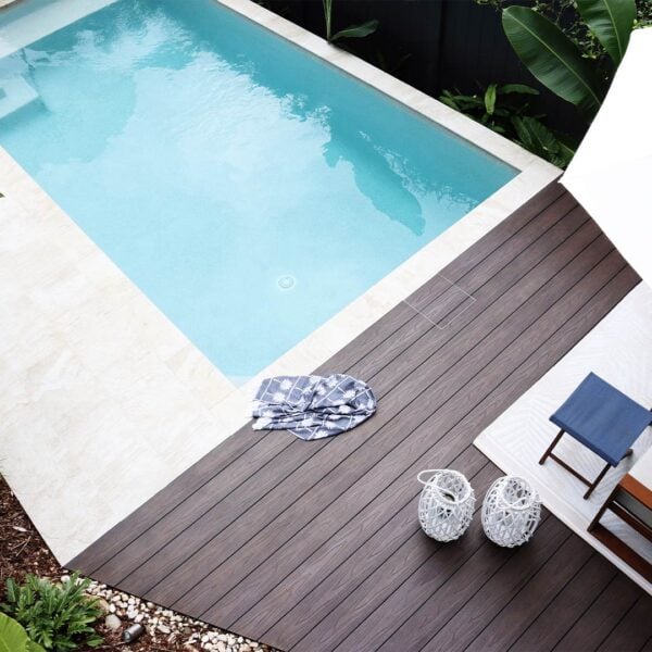 HIDE Skimmer Cover with brown timber decking inlay installed next to modern pool with tile coping.