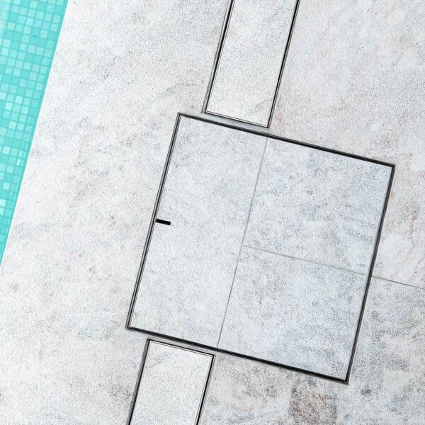 Flush sitting HIDE Skimmer Cover installed with grey tile inlay close up.