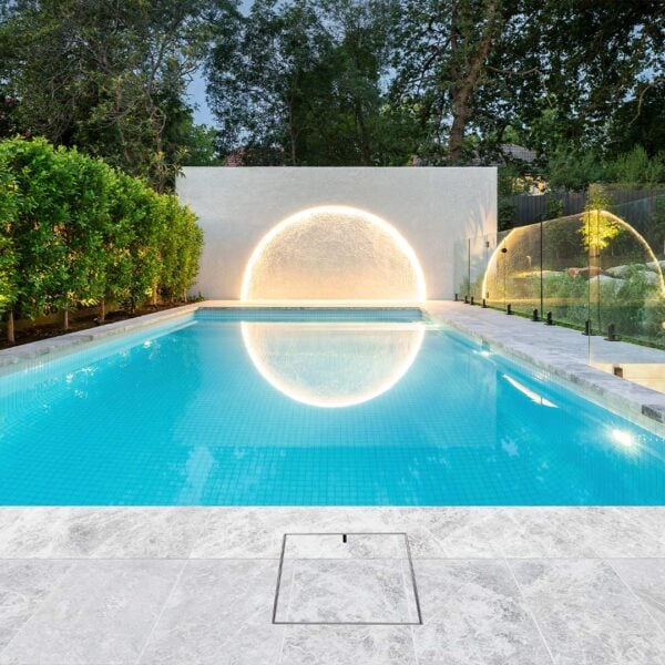 Stainless Steel HIDE Skimmer Lid installed with grey tile inlay next to modern pool.