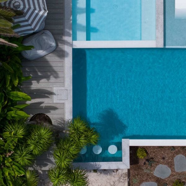 Stainless Steel HIDE Skimmer Cover next to modern pool with tropical plants.