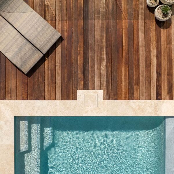 Birds-eye view of HIDE Skimmer Cover installed with cream tile inlay next to pool and decking.
