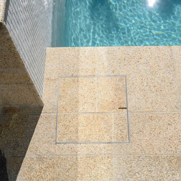 HIDE Stainless Steel Skimmer Cover with cream tile inlay and tile pattern running through Cover to create a seamless pooldeck.